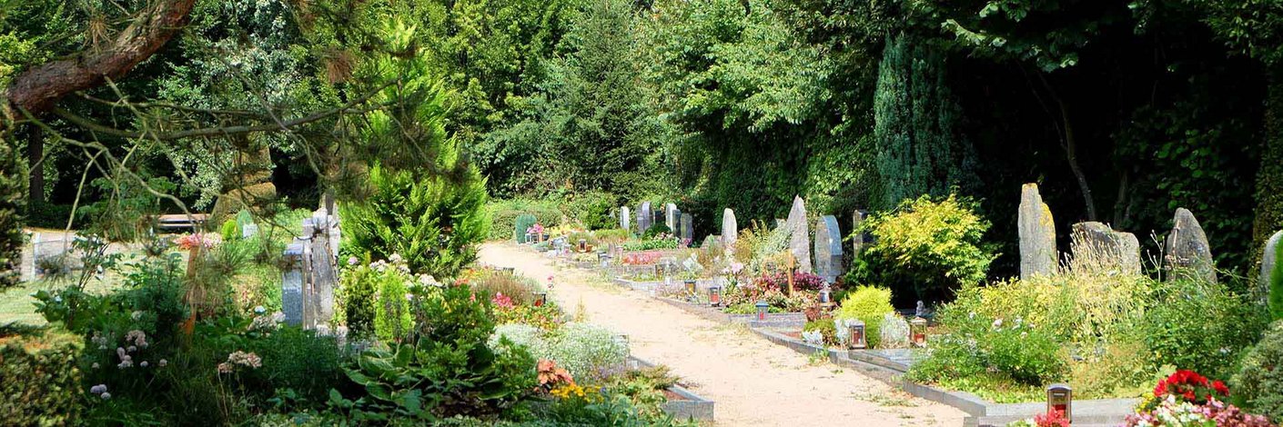 Gräber mit Grabsteinen an einem Weg auf einem Friedhof
