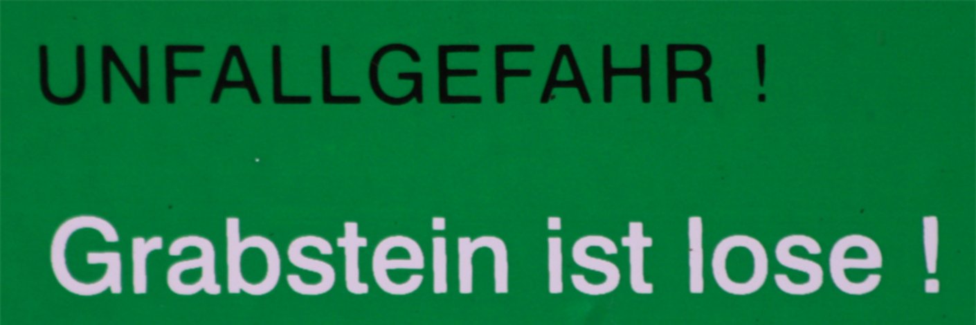 Schild mit Hinweis auf lockeren Grabstein - Unfallgefahr