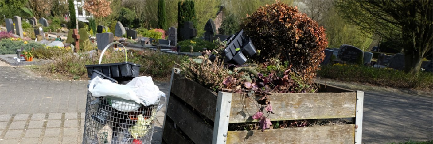 Mülleimer und Behältnis für Grünabfälle auf einem Friedhof